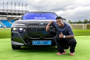 Vinicius posa junto a BMW eléctrico 4x4, destaque parrilla distintiva.