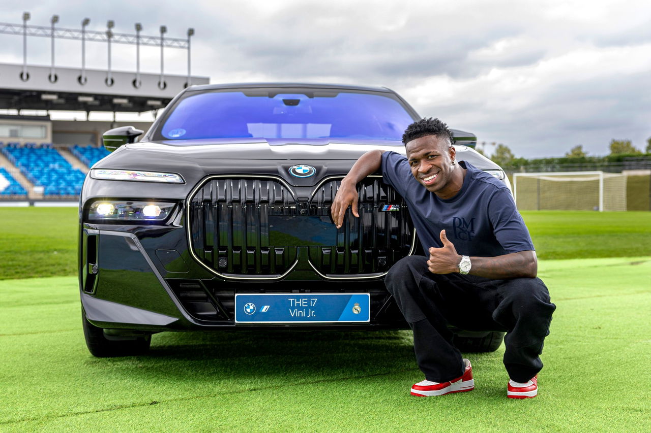 Vinicius posa junto a BMW eléctrico 4x4, destaque parrilla distintiva.