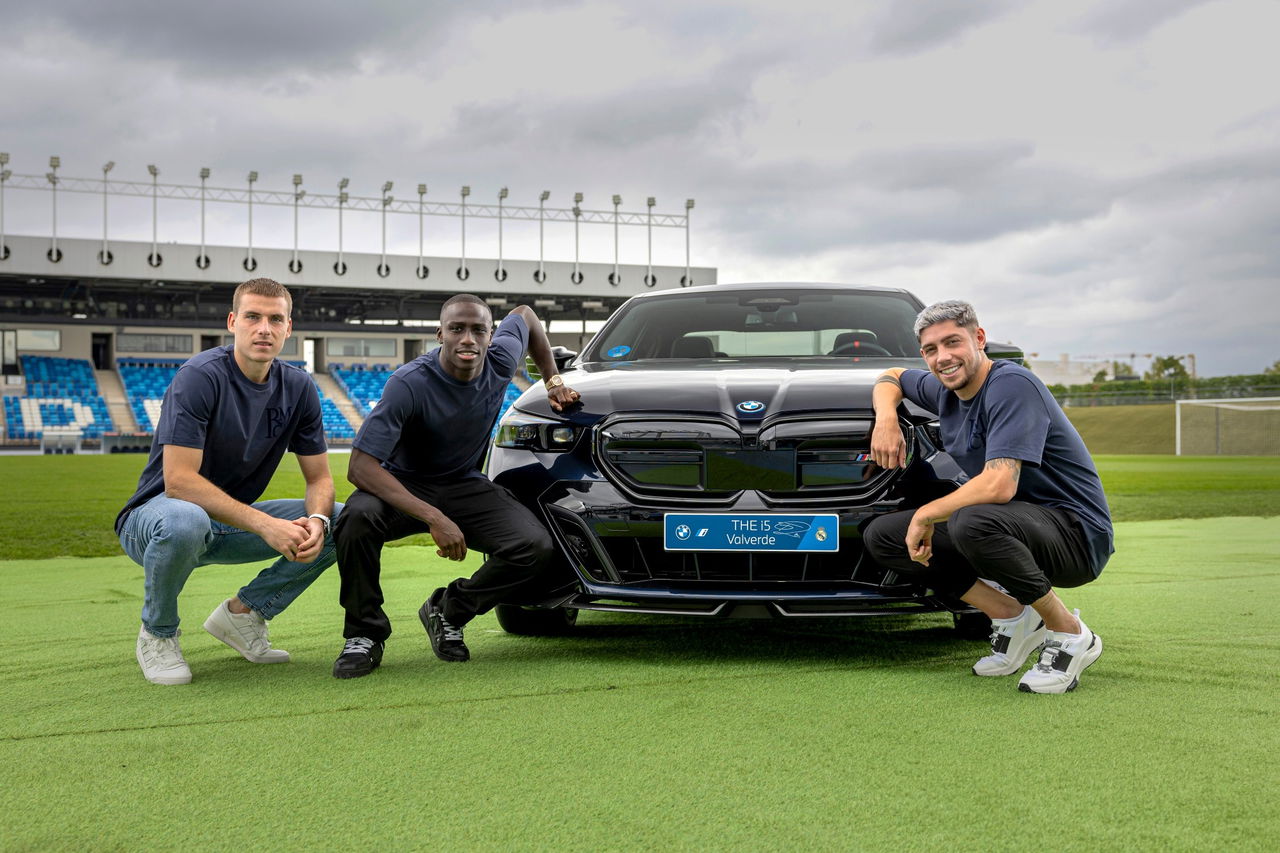 La trasera y el lateral de un BMW eléctrico posan junto a dos individuos.