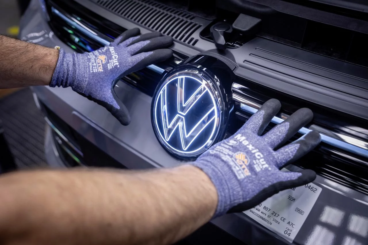 Operario inspeccionando calidad en emblema Volkswagen en fábrica