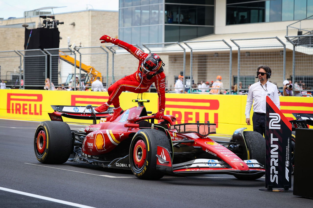 Carlos Sainz celebra el MVP junto a su Ferrari en el paddock, con Alonso al fondo.