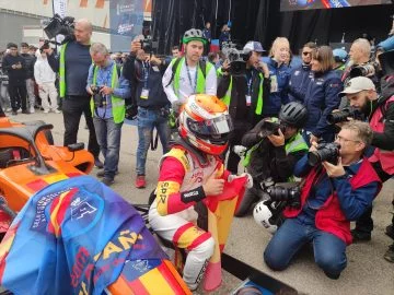 Juan Cota celebra victoria circuito, rodeado prensa y su monoplaza