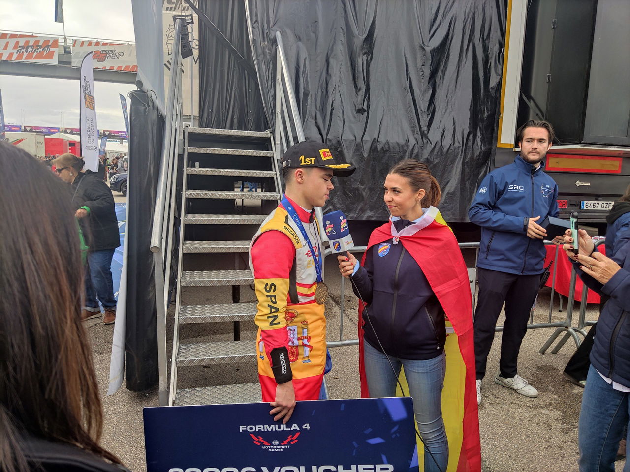 Juan Cota celebra victoria emocionado circuito local, rodeado de aficionados y prensa.