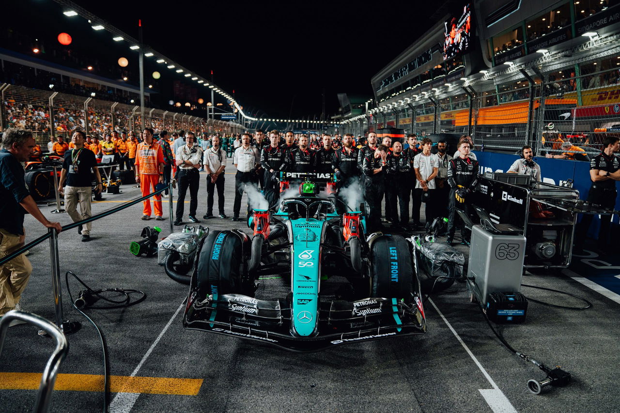 Un Mercedes F1 celebra victoria con equipo en pit lane nocturno