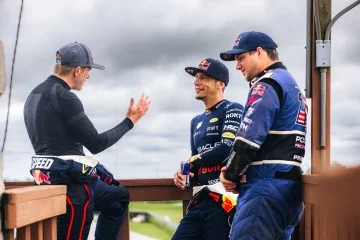 Tres pilotos de Red Bull conversan antes de competir. No se puede identificar un coche.