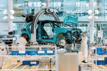 Vista de la línea de ensamblaje de Volkswagen con operarios y robots en proceso.