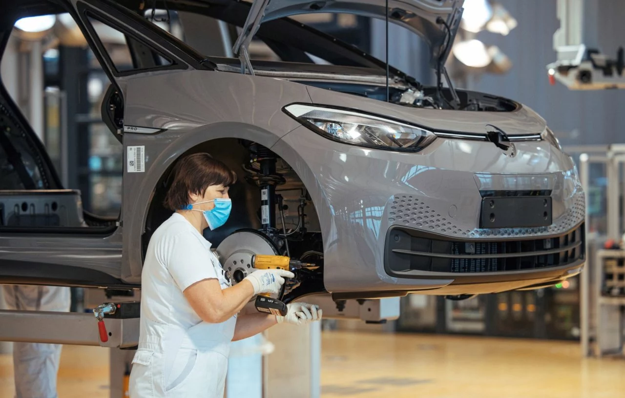 Imagen de trabajador en línea de montaje de Volkswagen con vehículo en proceso.