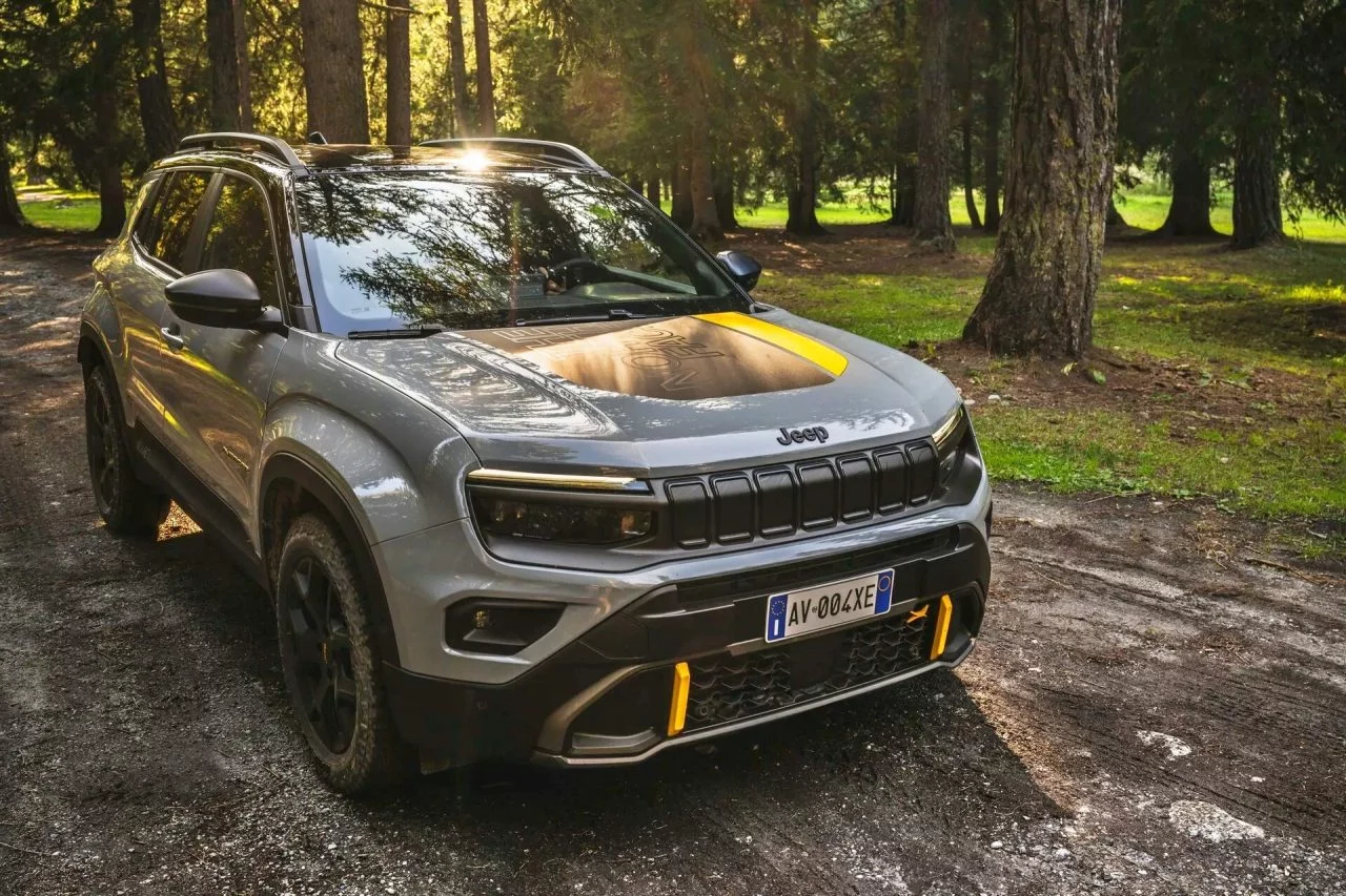 Vista delantera y lateral del Jeep Avenger 4xe The North Face Edition aparcado en el bosque.