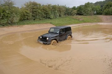 Jeep Wrangler superando obstáculo de barro con destreza y potencia del motor V6.