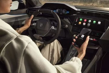 Vista del puesto de conducción del Peugeot e-408 con énfasis en su volante e instrumentación digital.