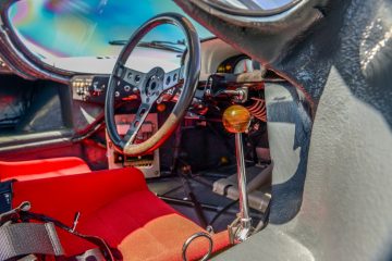 Cabina del Porsche 917K con volante clásico y panel de instrumentos de carreras.