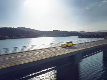 Vista lateral del Renault 5 eléctrico en entorno natural junto al lago.