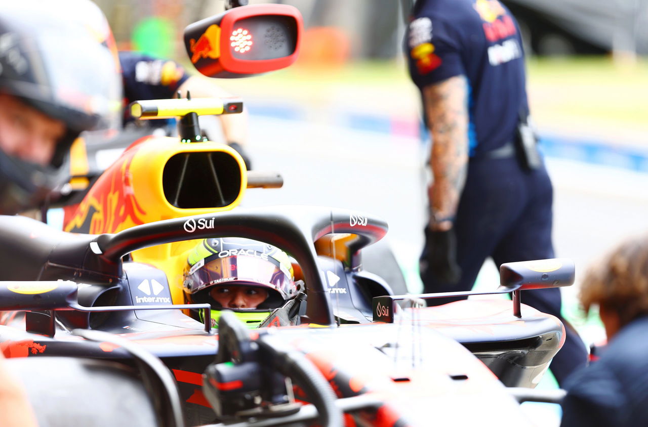 Primer plano de un monoplaza F1 en pits, enfocando al piloto y detalles aerodinámicos.