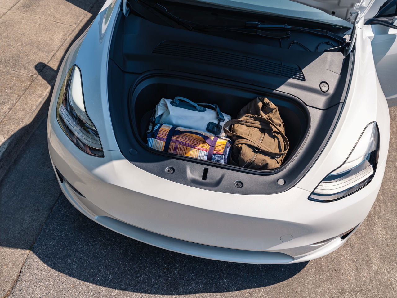 Vista del maletero delantero del Tesla Model Y con equipaje, mostrando su practicidad y espacio.