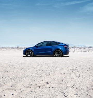 Vista lateral del Tesla Model Y en un entorno desértico, resaltando su diseño aerodinámico y líneas modernas.