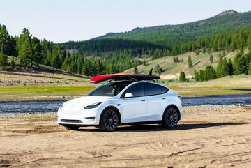 El Tesla Model Y muestra su elegante perfil lateral con un canoero en el techo.