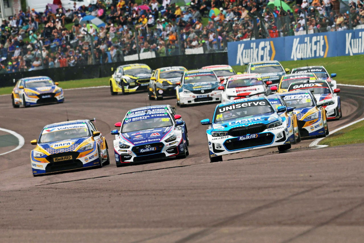 La imagen muestra una intensa carrera del BTCC, destacando la competitividad de los coches en pista.