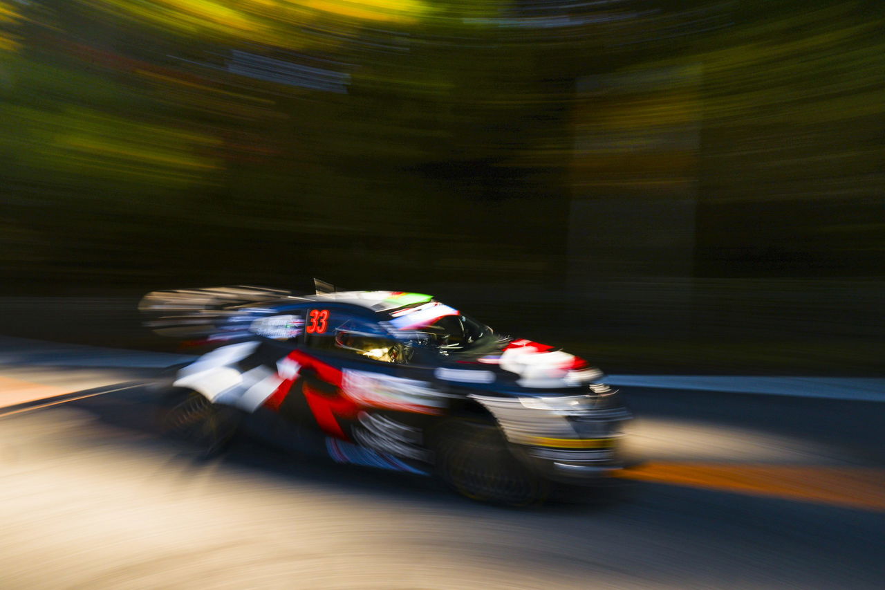 El coche de rally acelera en una curva, mostrando su diseño aerodinámico.