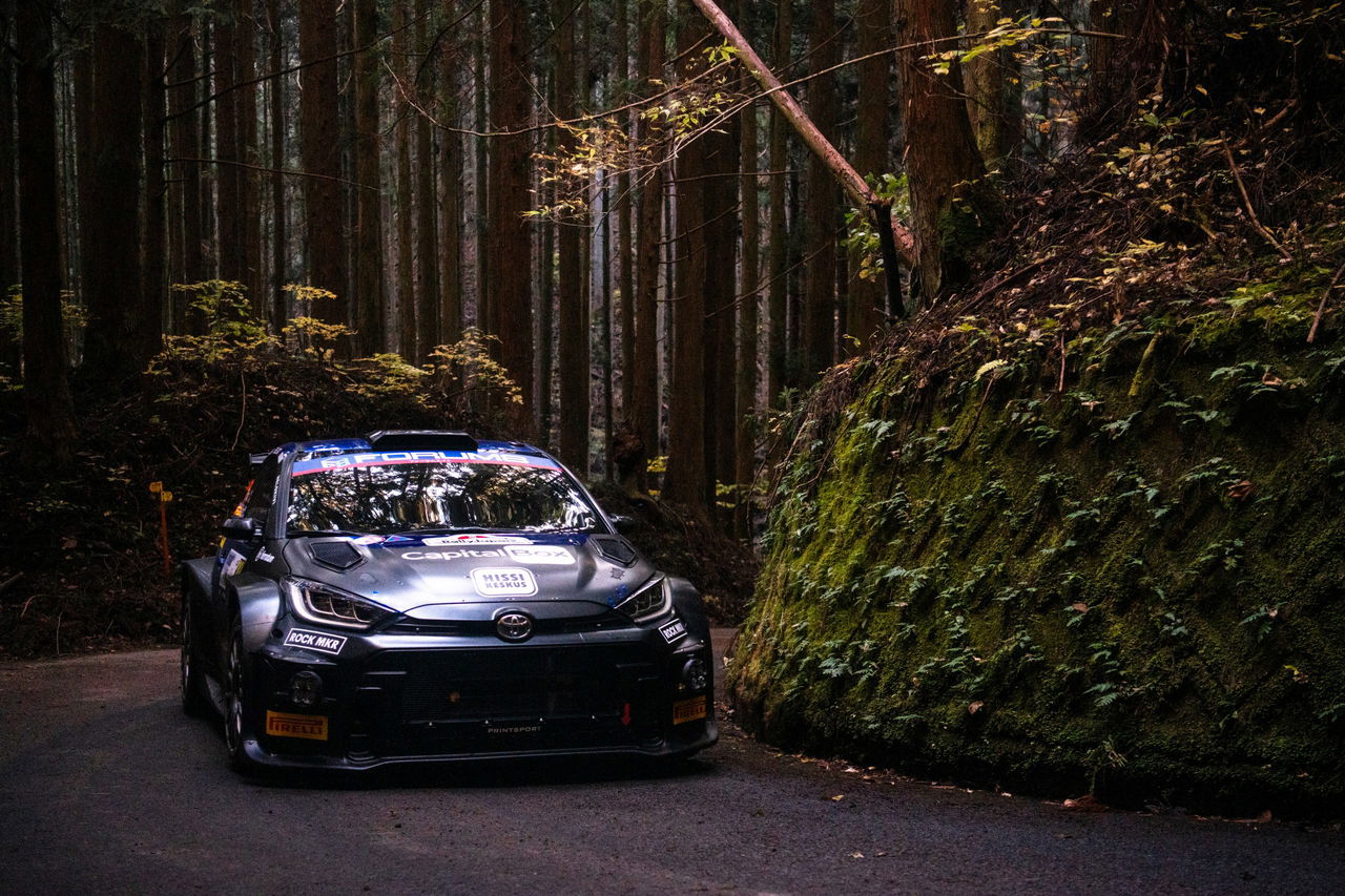 El coche de rally atraviesa un estrecho camino forestal en Japón.