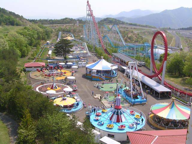 Vista aérea de un parque de atracciones en Sendai, rodeado de montañas.