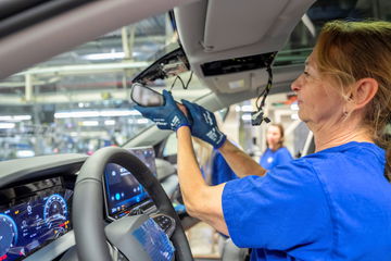 Trabajador de Volkswagen instalando componentes en una línea de producción.