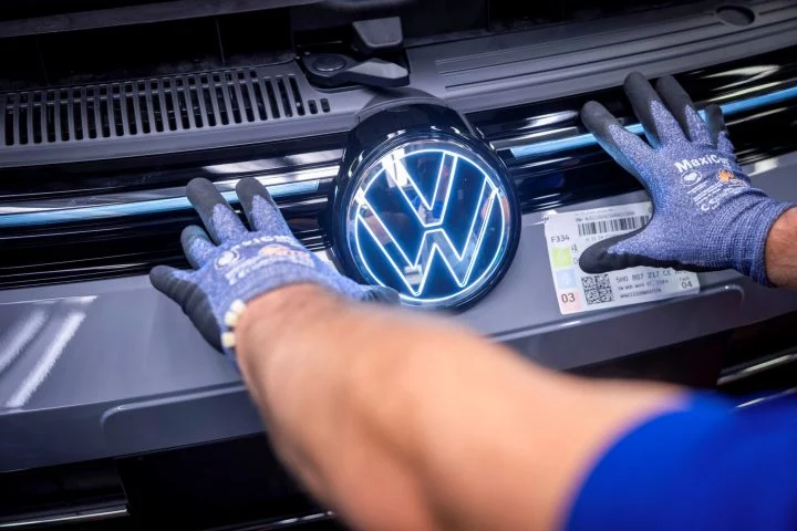 Un trabajador coloca el emblema de Volkswagen en una línea de montaje.