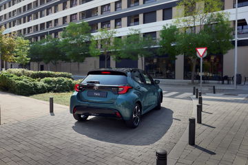 Vista lateral y trasera del Toyota Yaris 2025 en un entorno urbano.