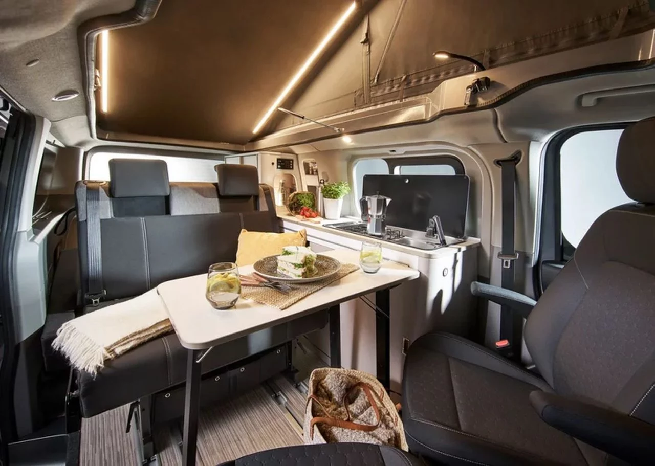 Interior versátil con mesa y asientos cómodos, ideal para viajar. 