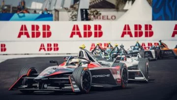 Coches de Fórmula E compitiendo en circuito urbano, destacando su aerodinámica.