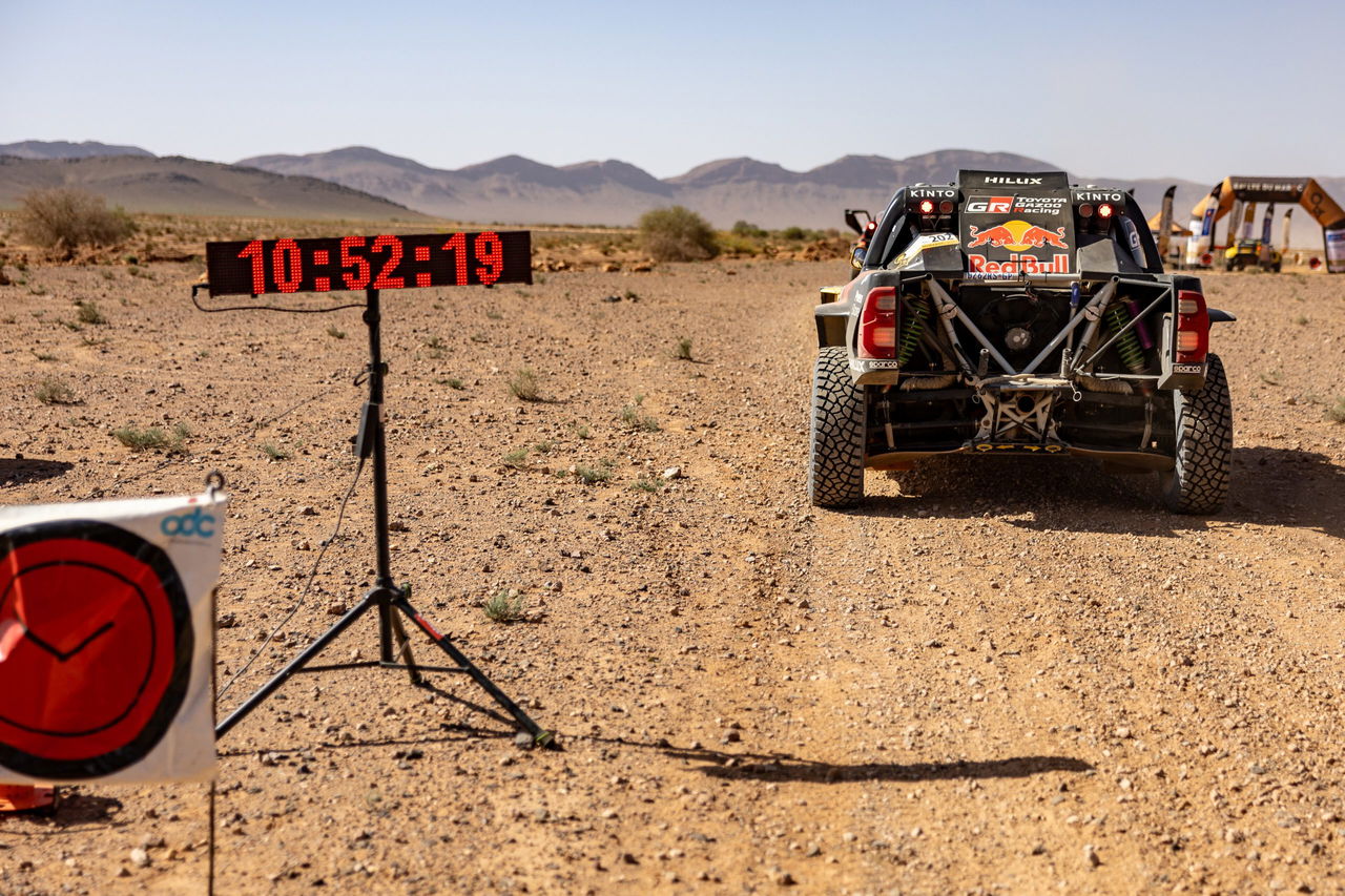 Vista trasera de un coche del Rally Dakar con un cronómetro marcando el tiempo.