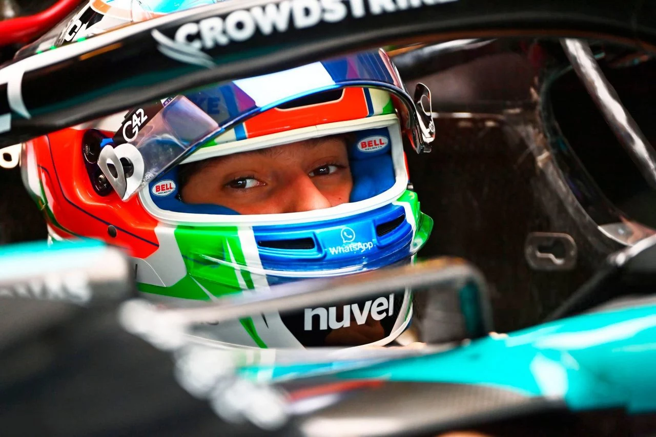 Piloto en cockpit preparado para carrera, mostrando los colores del casco