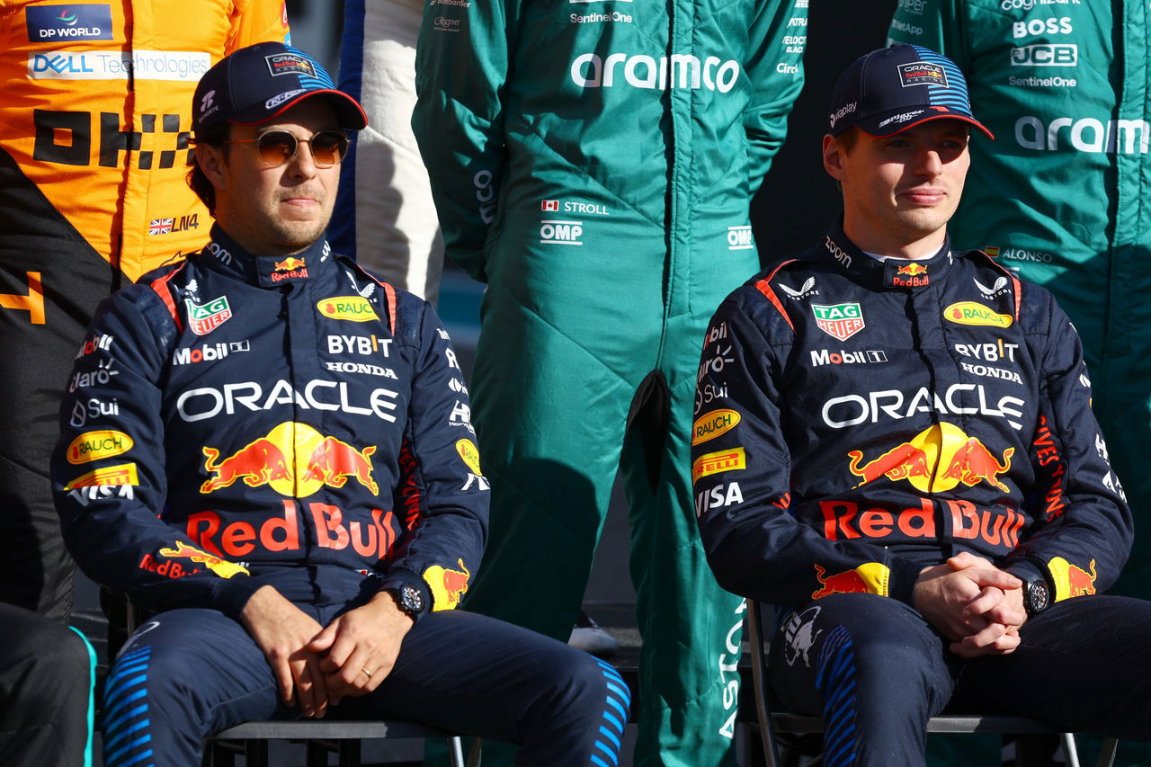 Checo Pérez y Max Verstappen posando en equipo, mostrando la indumentaria de Red Bull Racing.