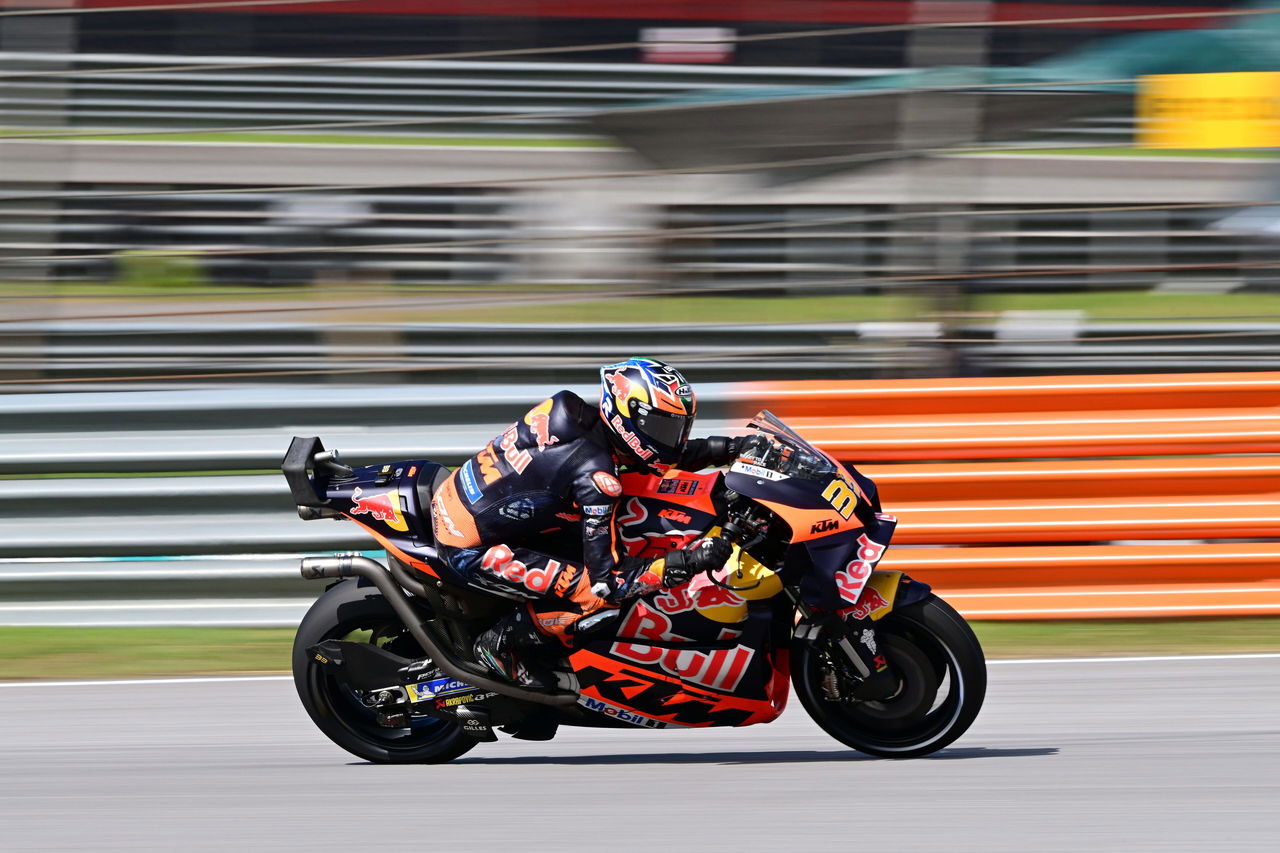 Piloto de KTM compitiendo en alta velocidad en una pista de MotoGP.