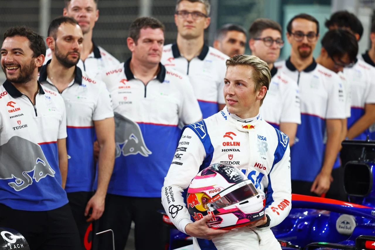 Liam Lawson posando con su casco, rodeado del equipo Red Bull.