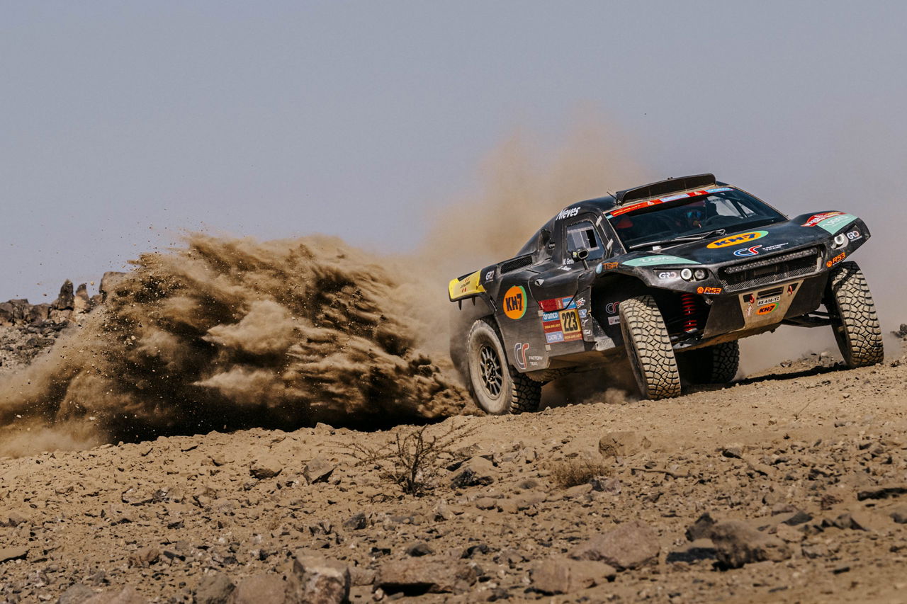 La imagen muestra un vehículo compitiendo en el Rally Dakar, enfrentándose a un terreno desafiante.