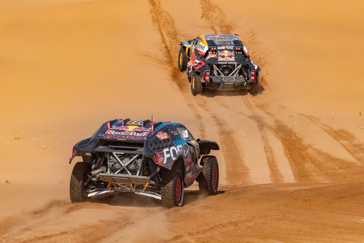 Dos vehículos rally compiten en las dunas del Dakar 2025, mostrando su robustez y agilidad.