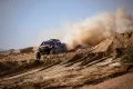 Un coche de rally surca las dunas del desierto, creando una nube de polvo impresionante.