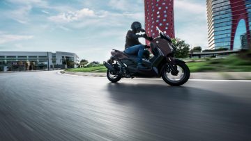 La Yamaha XMAX 2025 se presenta en un entorno urbano, destacando su diseño moderno y deportivo.