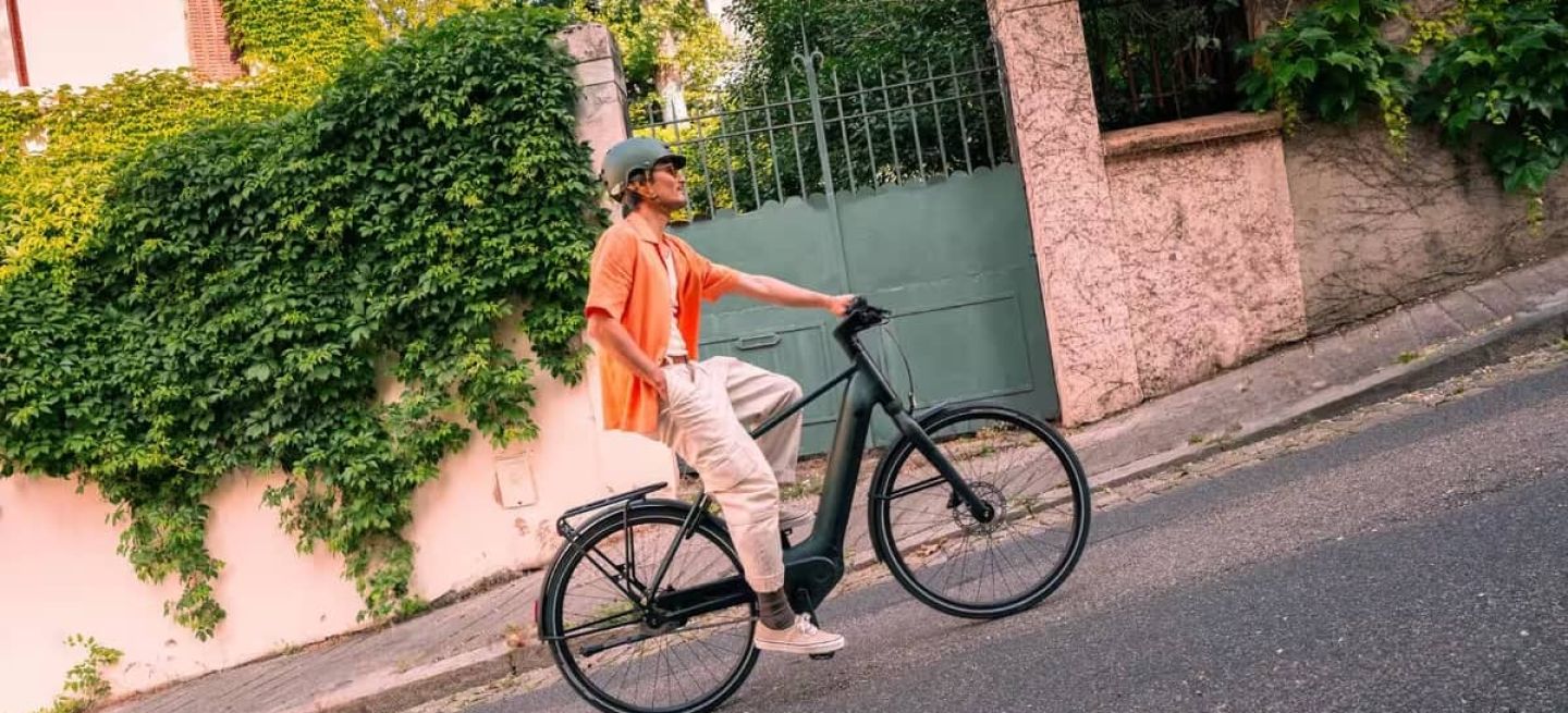 Persona desplazándose en una bicicleta urbana junto a una valla