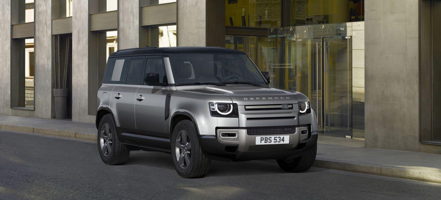 Vista angular del Land Rover Defender en un entorno urbano, destacando su robusta presencia.