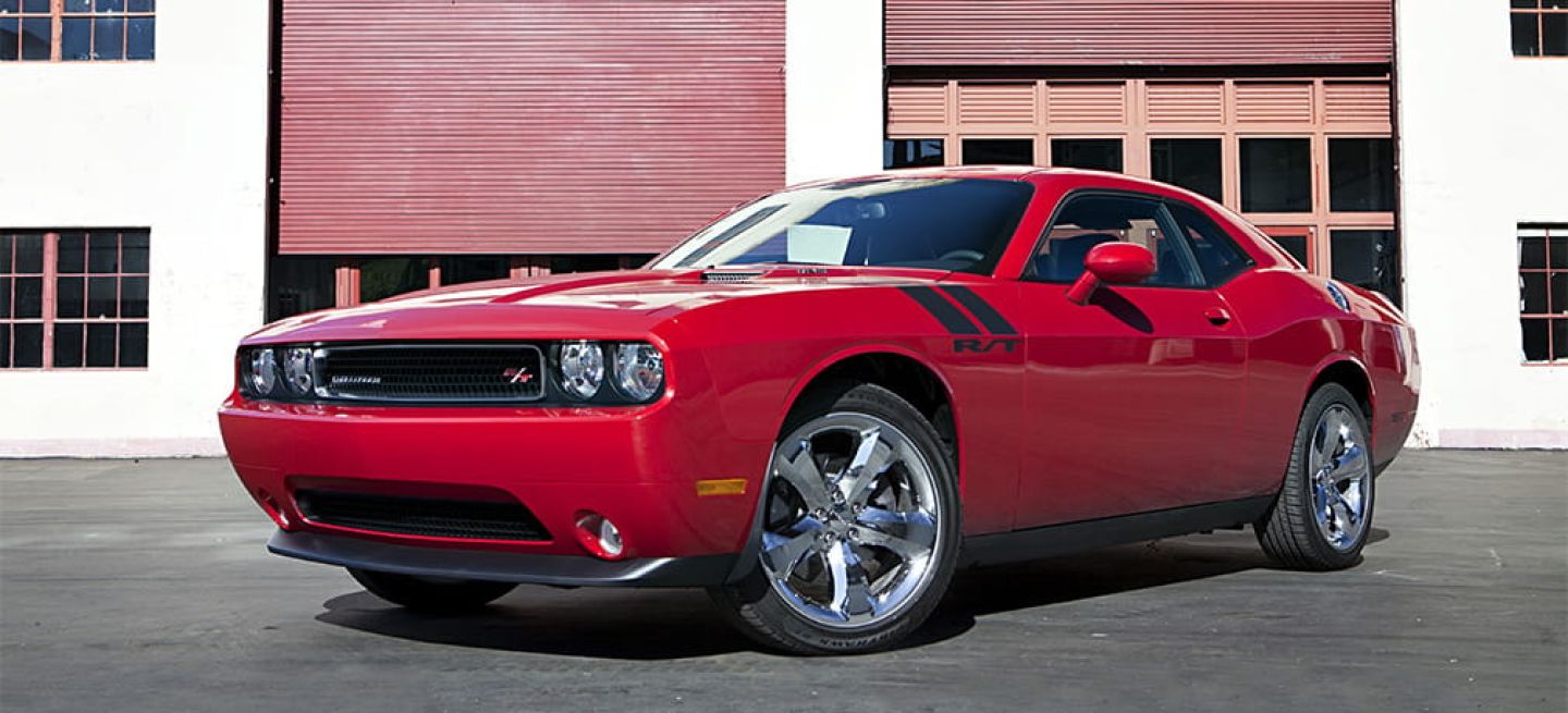 Vista lateral de Dodge Challenger en rojo, mostrando su perfil musculoso y deportivo.