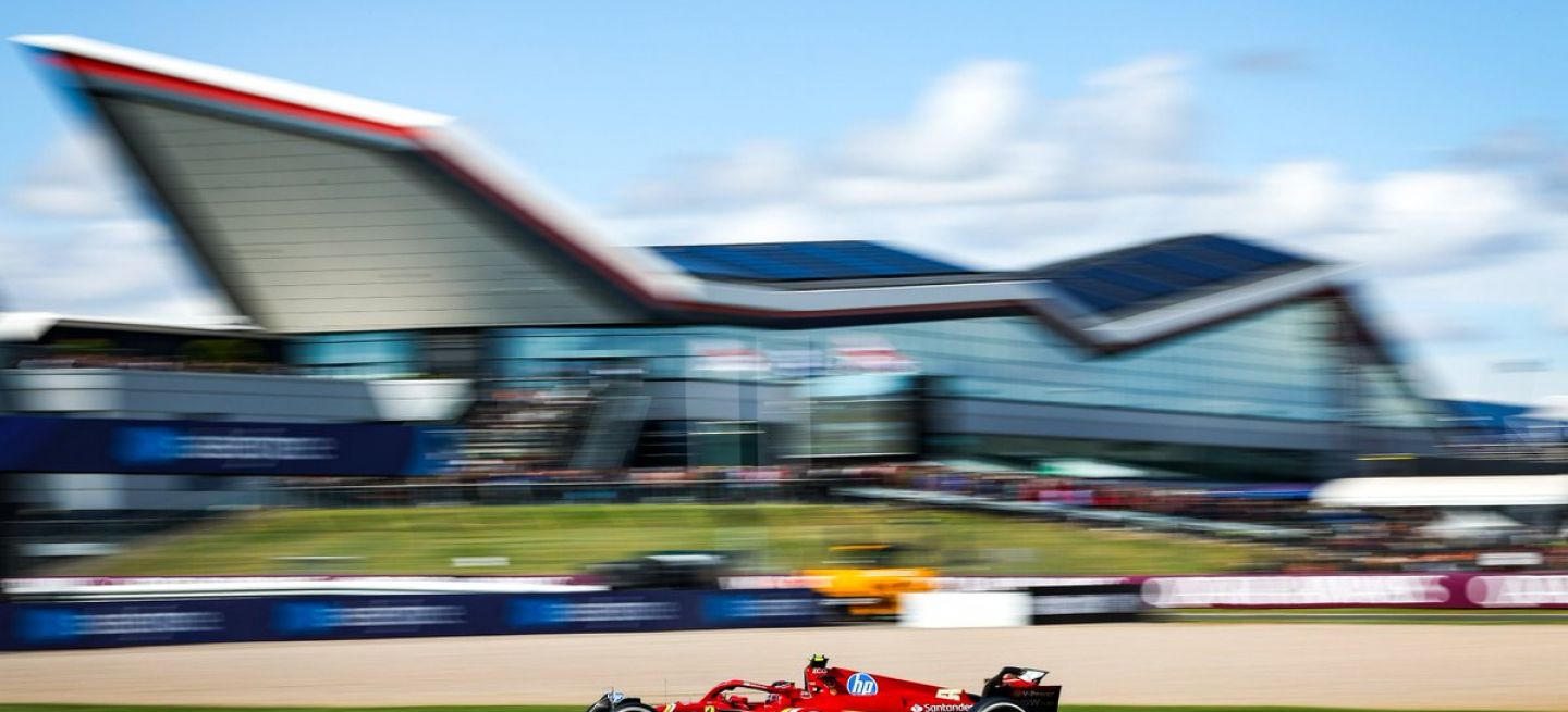 Un F1 de Ferrari negociando una curva en Silverstone bajo cielo azul