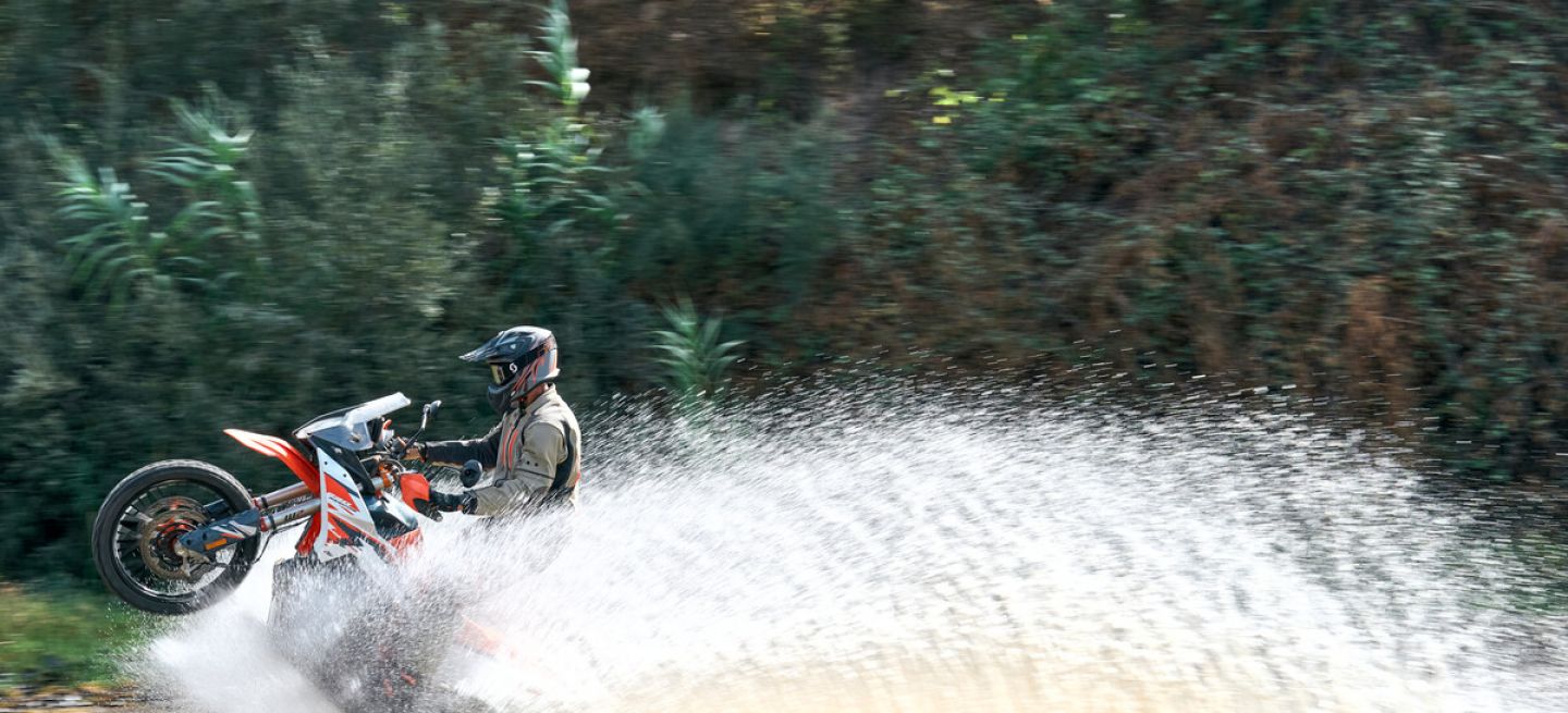 Imagen de una KTM sobre terreno acuático, mostrando su rendimiento en situaciones extremas.