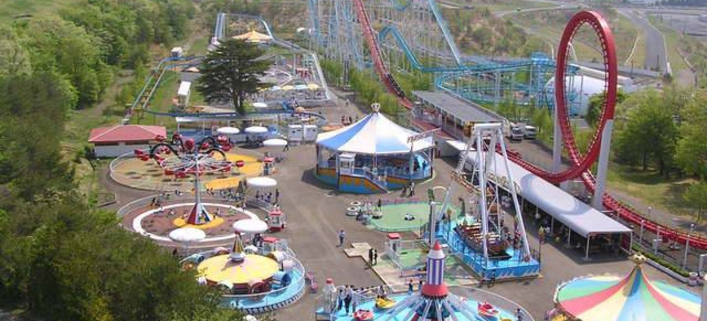 Vista aérea de un parque de atracciones en Sendai, rodeado de montañas.